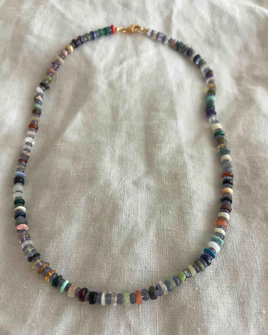 Necklace with multicolored beads on a light fabric background
