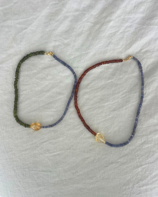 Two beaded necklaces on a textured white surface