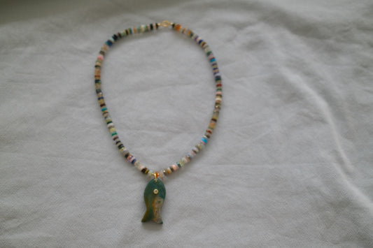 Necklace with a green pendant on a white fabric background