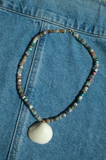 Necklace with a shell pendant on a blue denim background