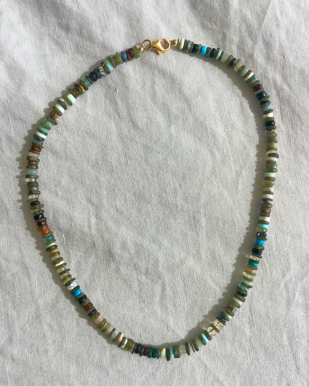 Necklace with multicolored beads on a white fabric background