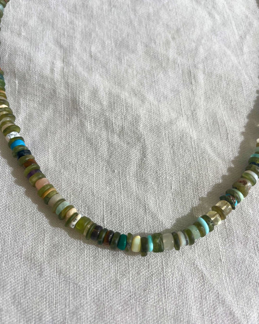 Necklace with small multicolored beads on a white fabric background