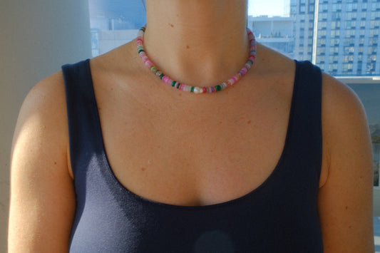Person wearing a colorful beaded necklace with a cityscape in the background