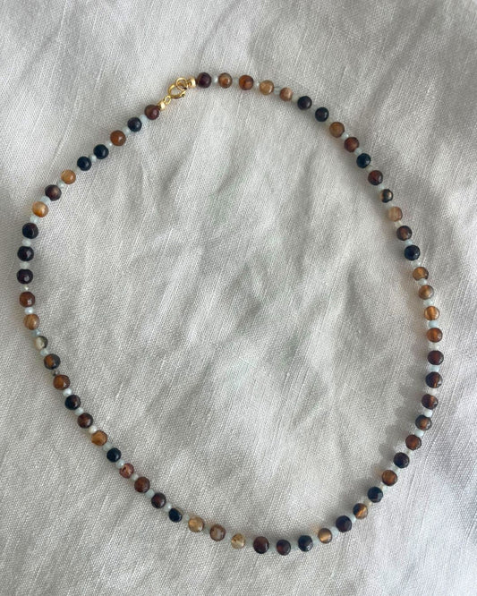 Multicolored beaded necklace on a gray fabric background