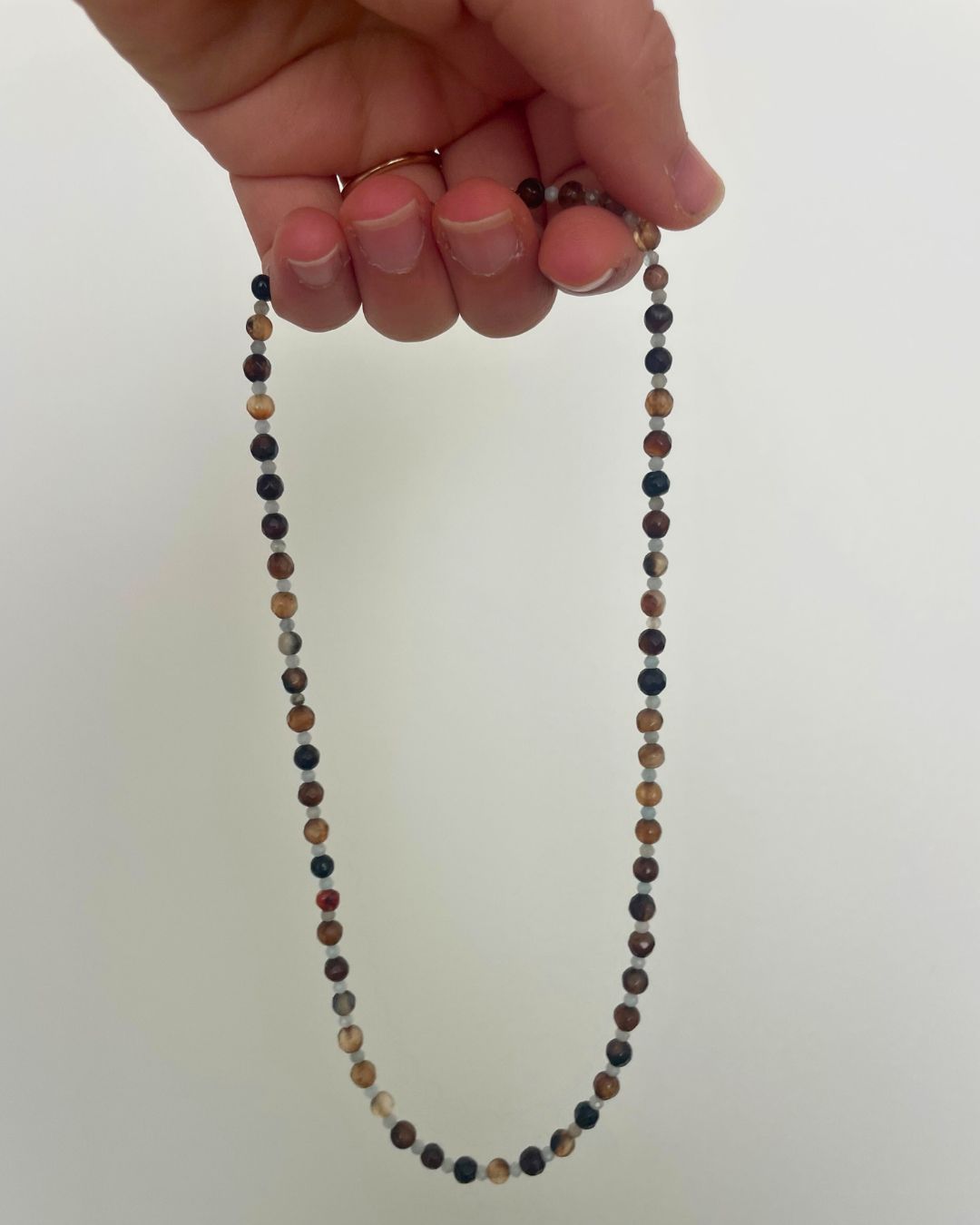 Hand holding a beaded necklace against a white background