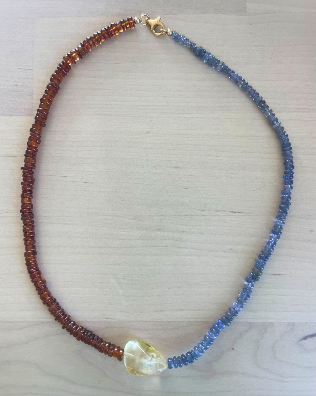 Necklace with blue and brown beads on a light wooden surface