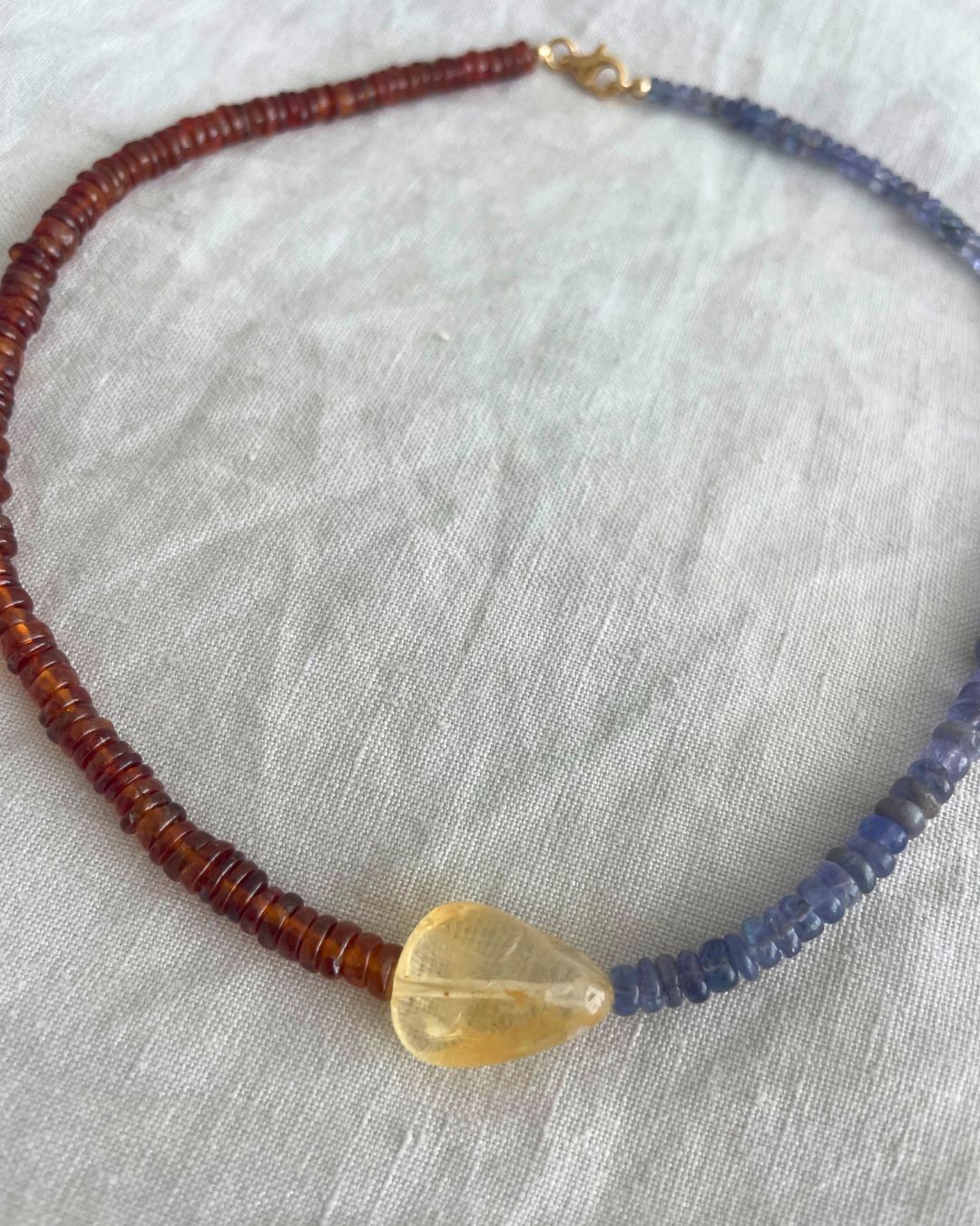 Necklace with brown, blue, and yellow beads on a light fabric background