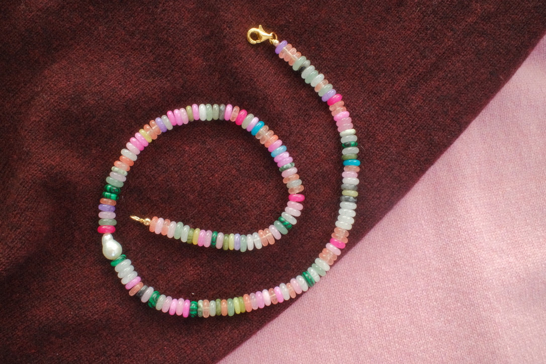 Multicolored beaded necklace on a textured fabric background