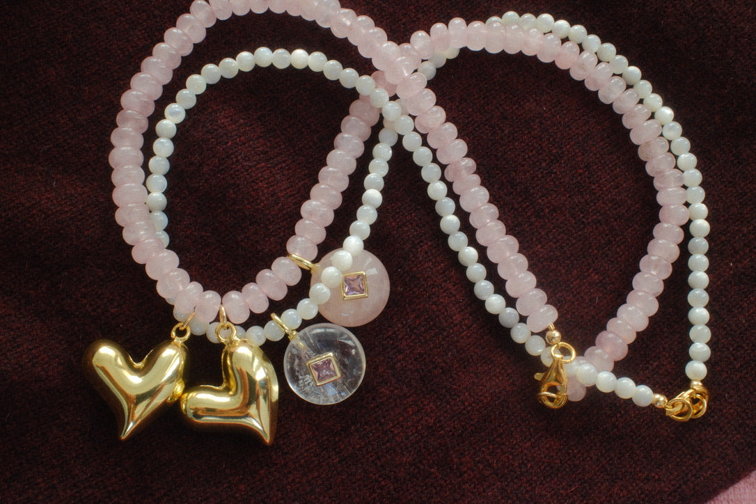 Two pearl bracelets with gold charms on a dark background