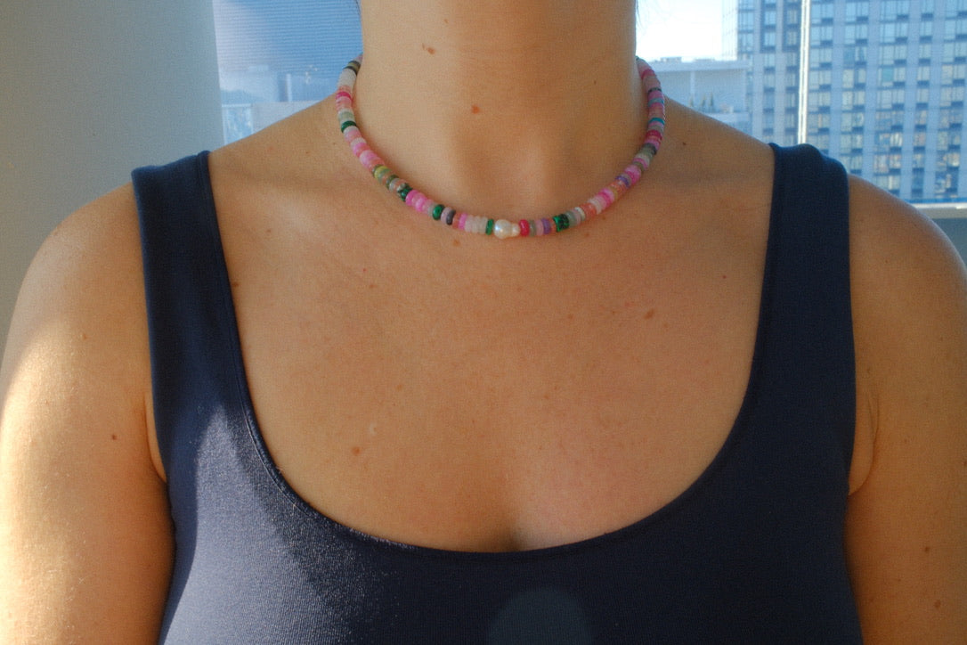 Person wearing a colorful beaded necklace with a blurred background