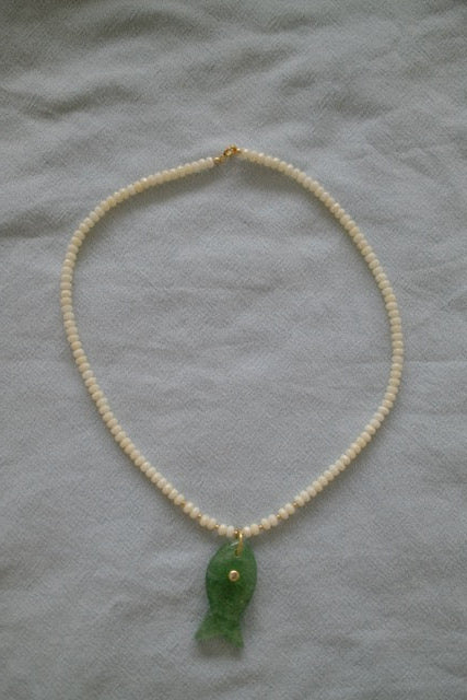 Necklace with a green pendant on a light gray fabric background