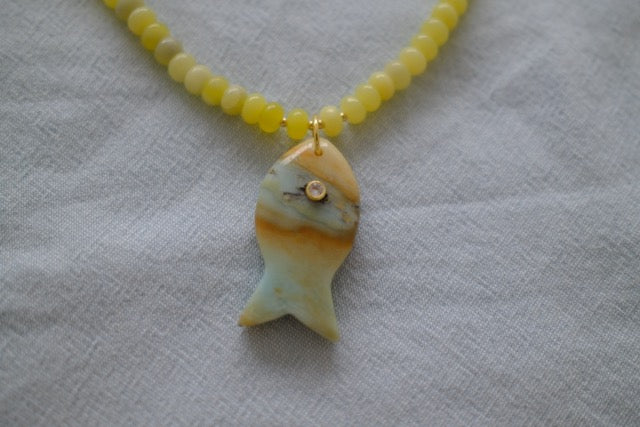 Necklace with a fish-shaped pendant on a light fabric background