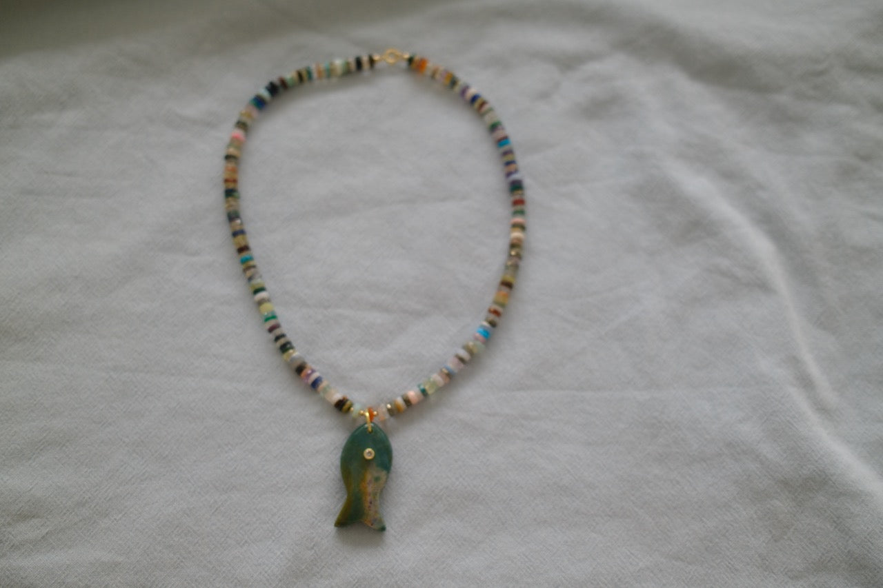 Necklace with a green pendant on a white fabric background