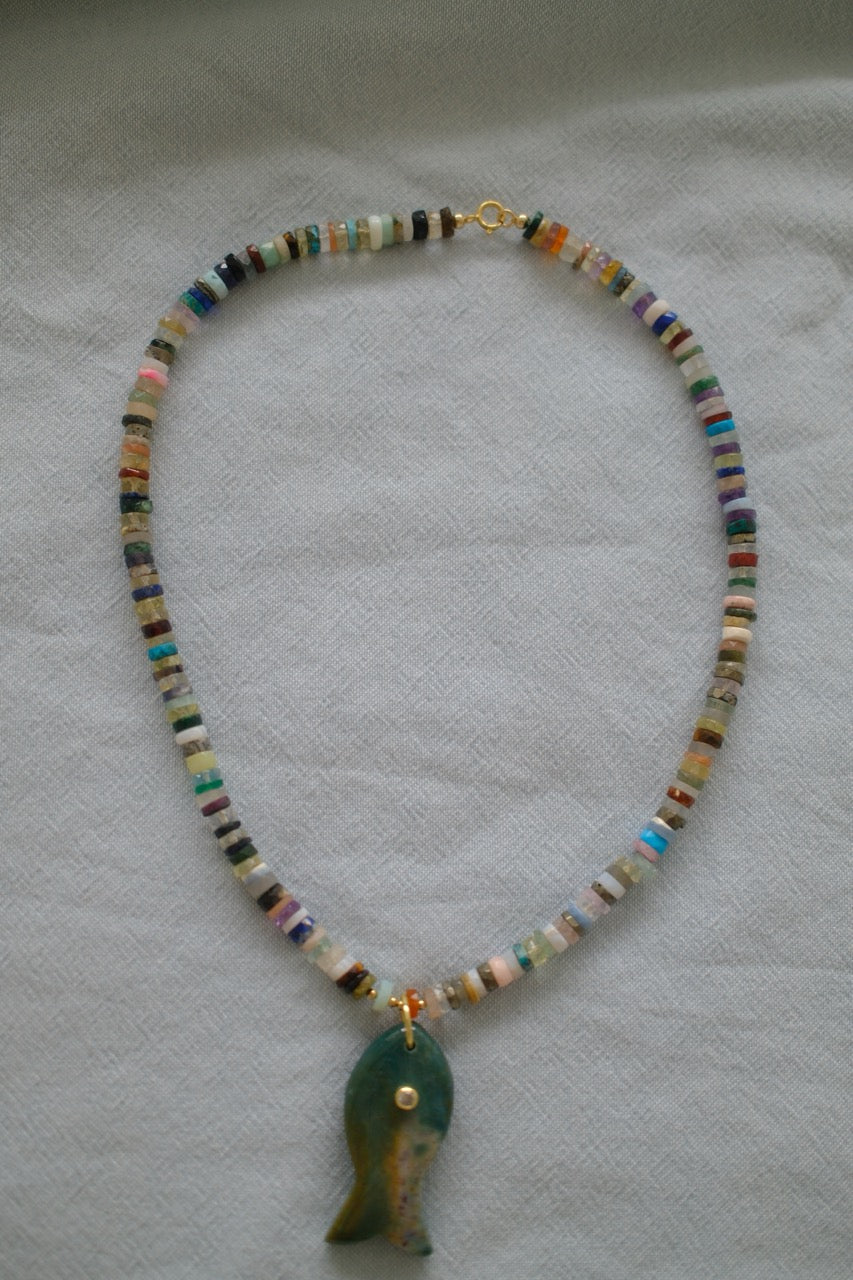 Beaded necklace with a green pendant on a light gray background
