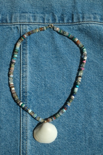 Necklace with a shell pendant on a blue denim background