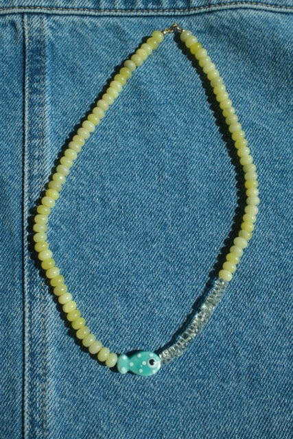 Necklace with fish charm on a blue denim background