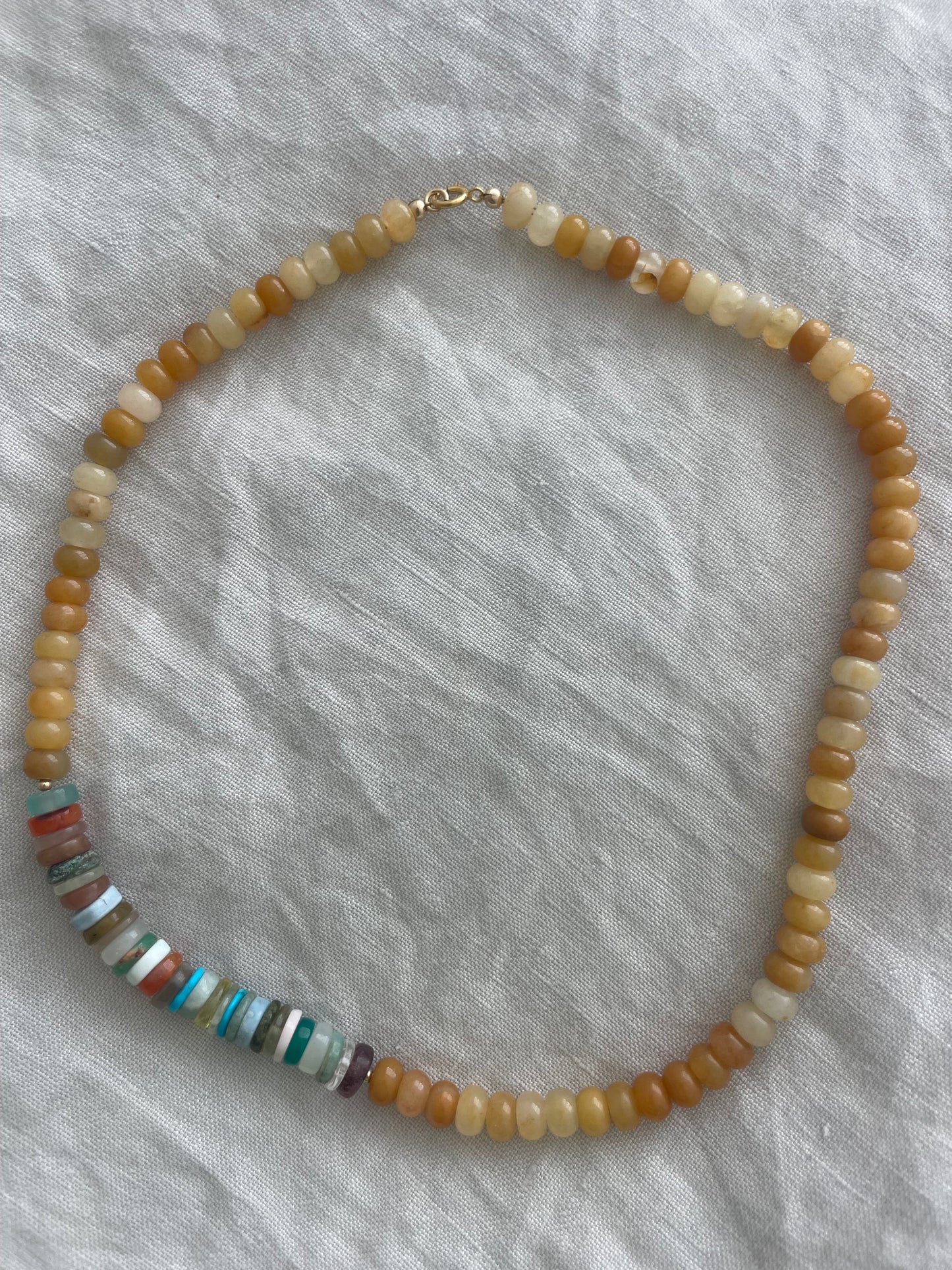 Beaded necklace with multicolored beads on a textured gray fabric background