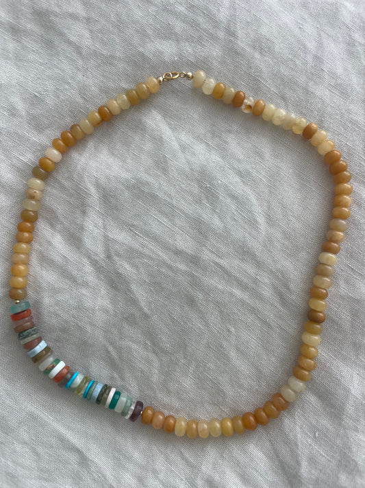 Beaded necklace with multicolored beads on a textured gray fabric background