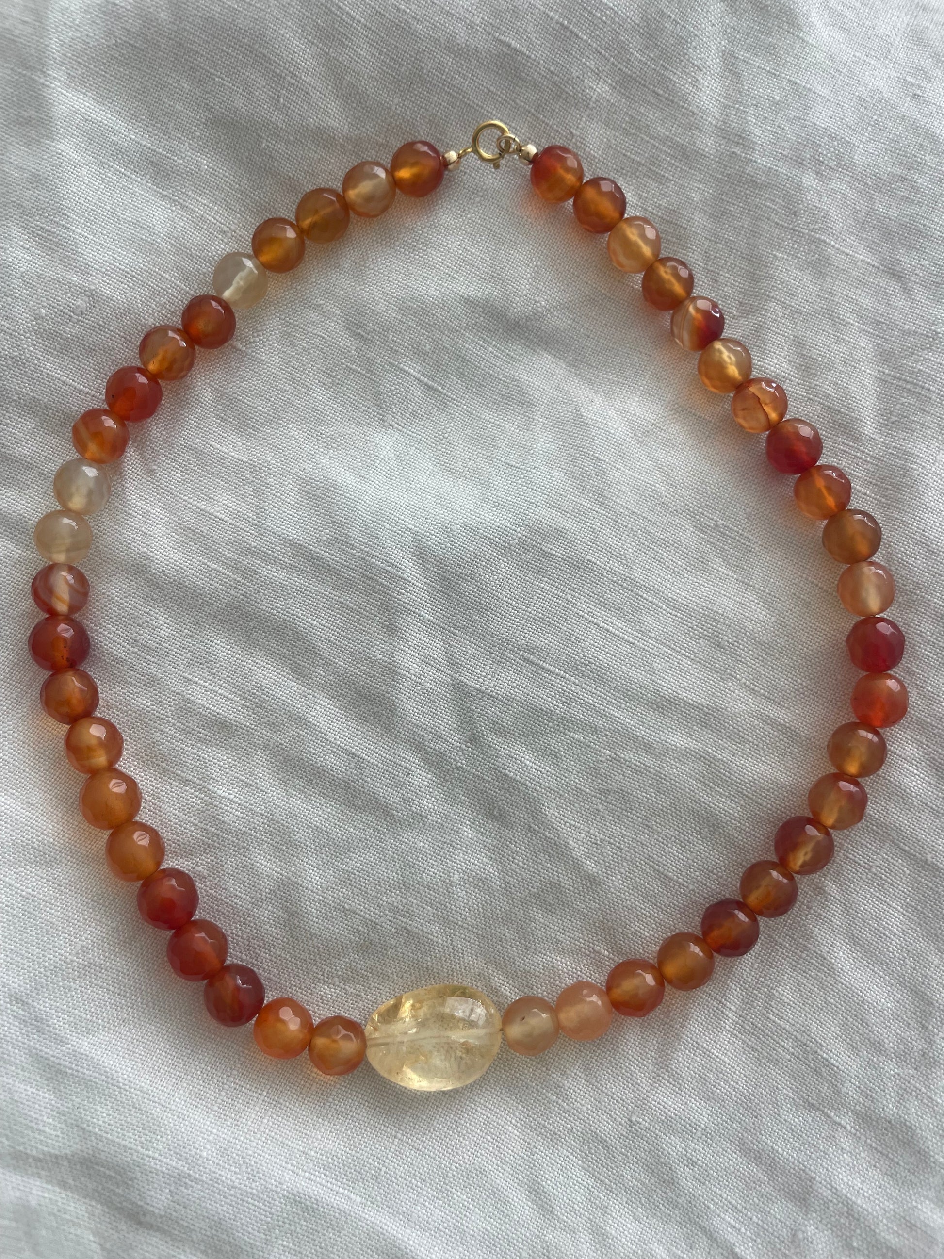 Beaded necklace with amber-colored beads on a light gray fabric background