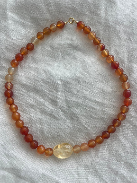 Beaded necklace with amber-colored beads on a light gray fabric background