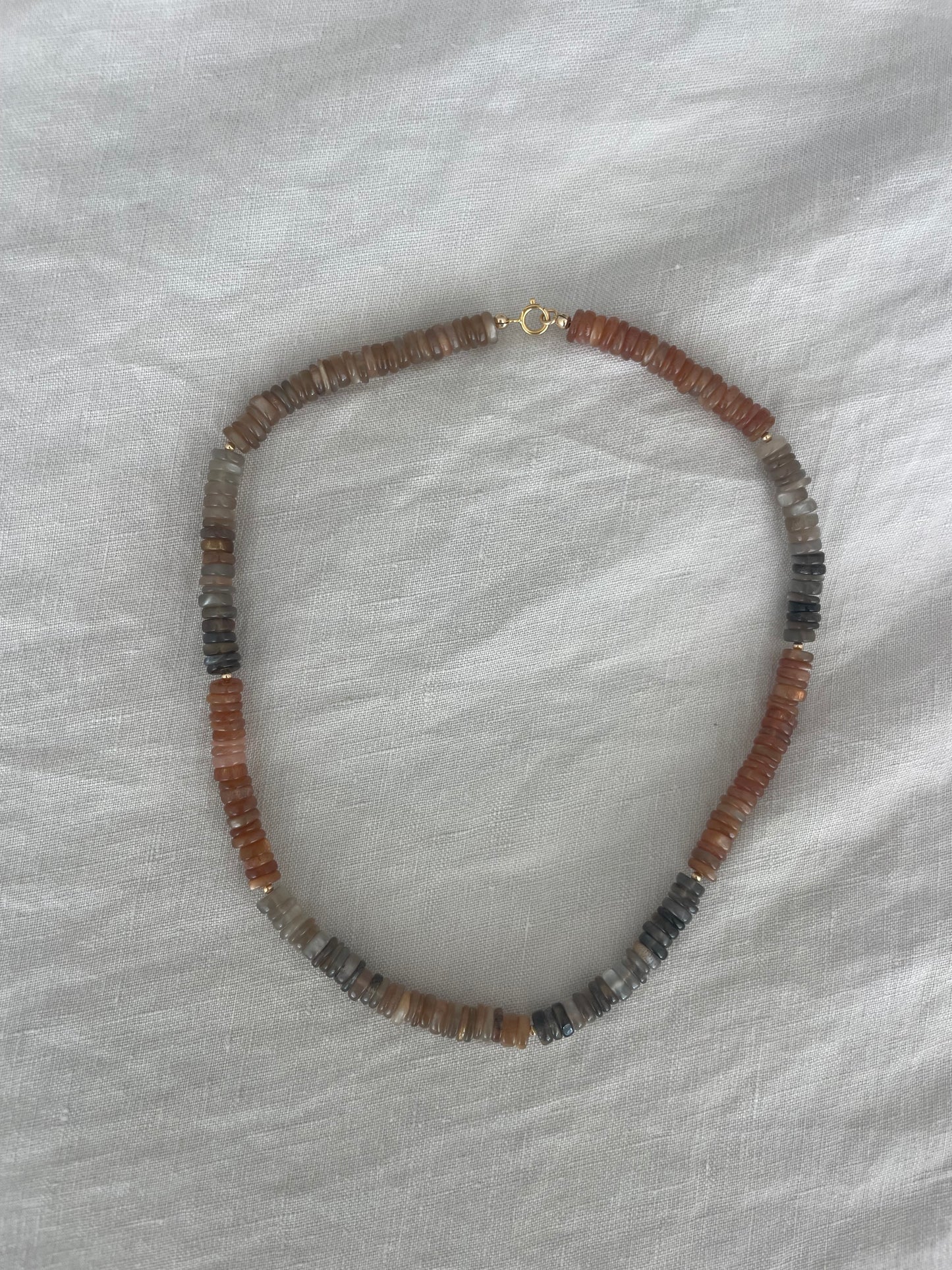 Necklace with brown and black beads on a white fabric background