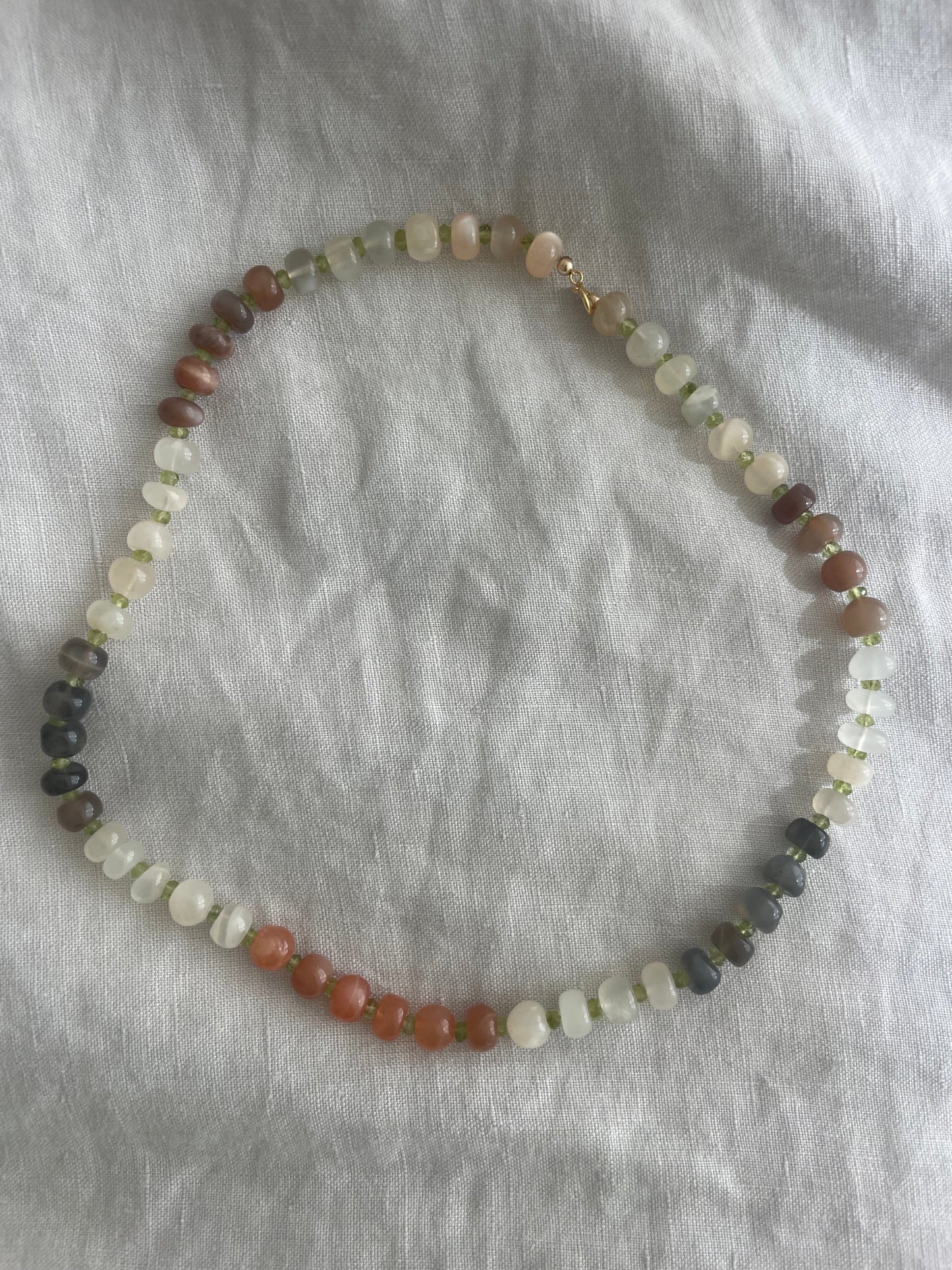 Necklace with multicolored beads on a gray fabric background
