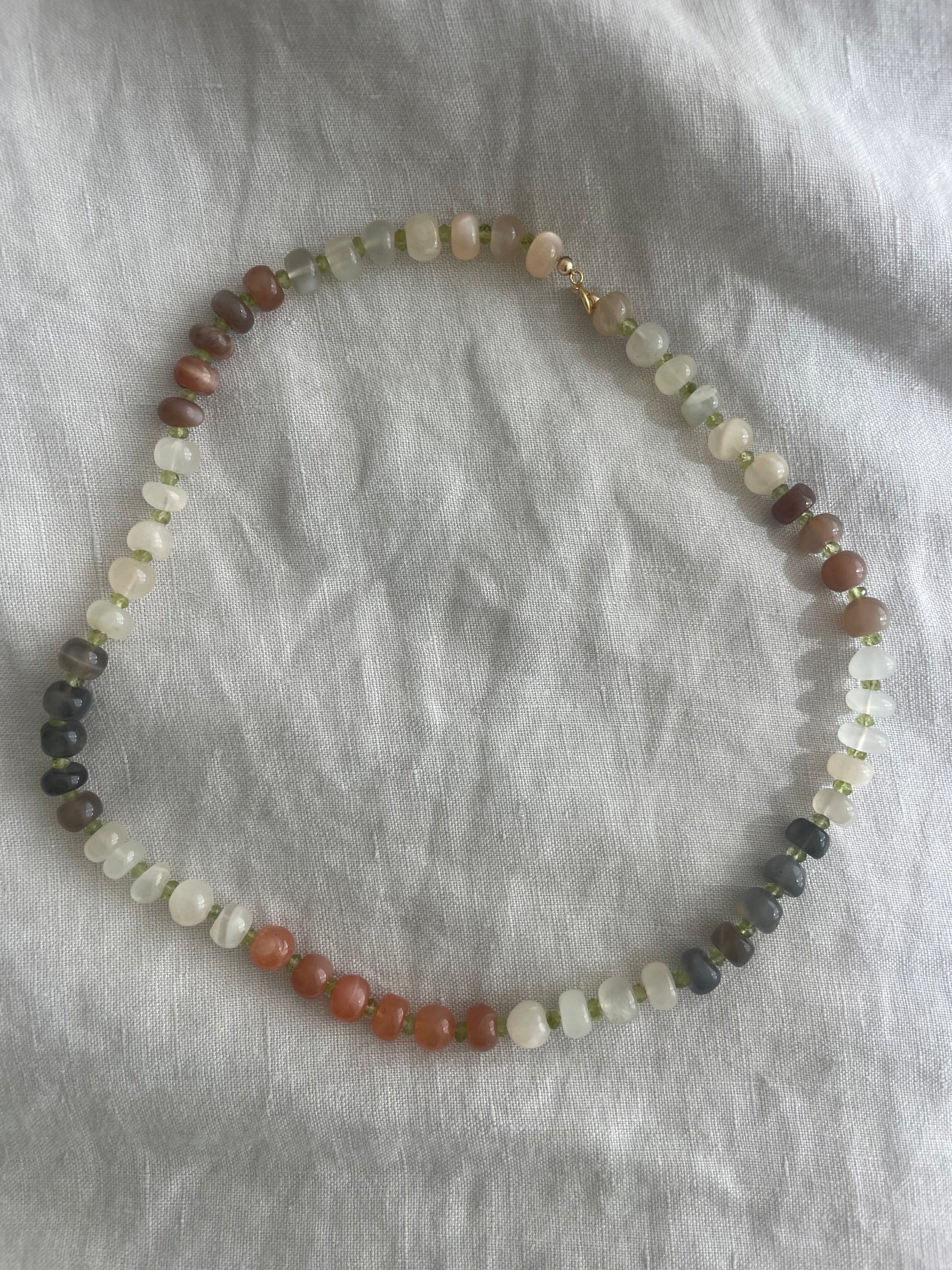 Necklace with multicolored beads on a gray fabric background