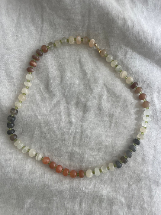 Necklace with multicolored beads on a gray fabric background