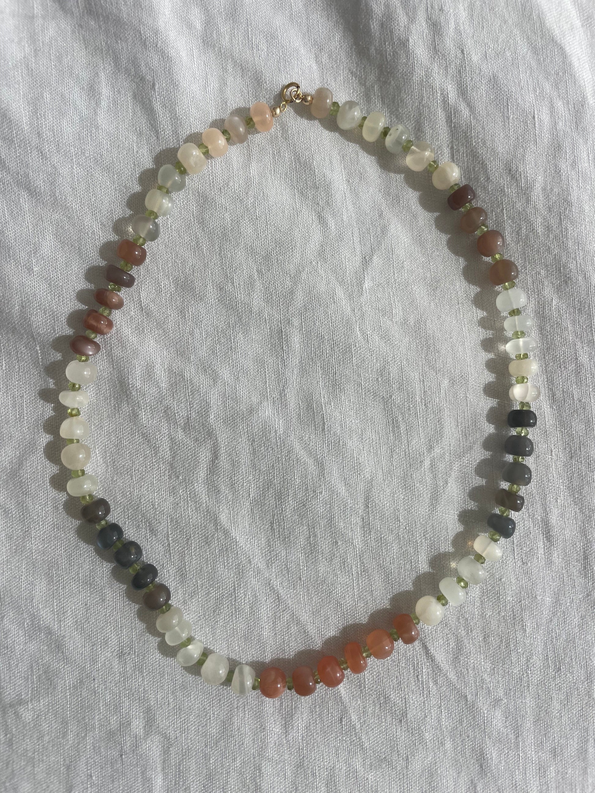 Multicolored beaded necklace on a gray fabric background