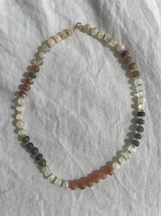 Multicolored beaded necklace on a gray fabric background