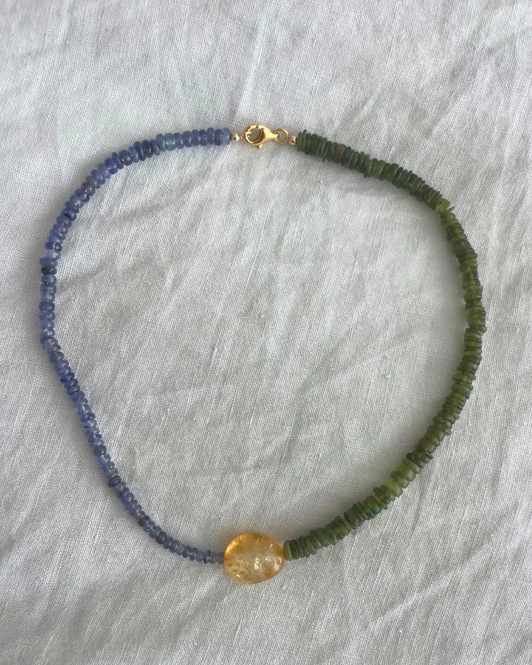 Necklace with blue and green beads on a gray background
