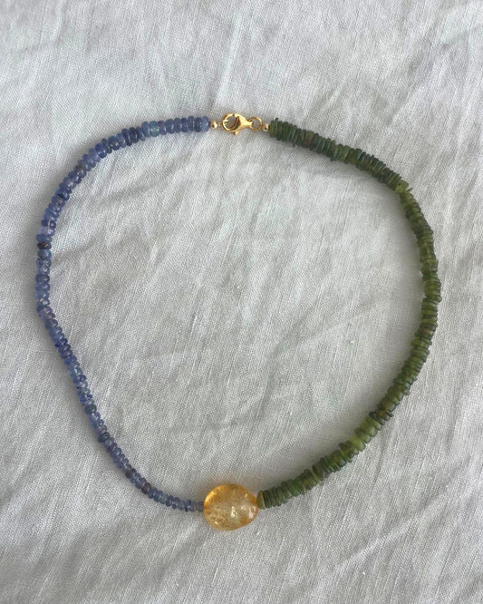 Necklace with blue and green beads on a gray background
