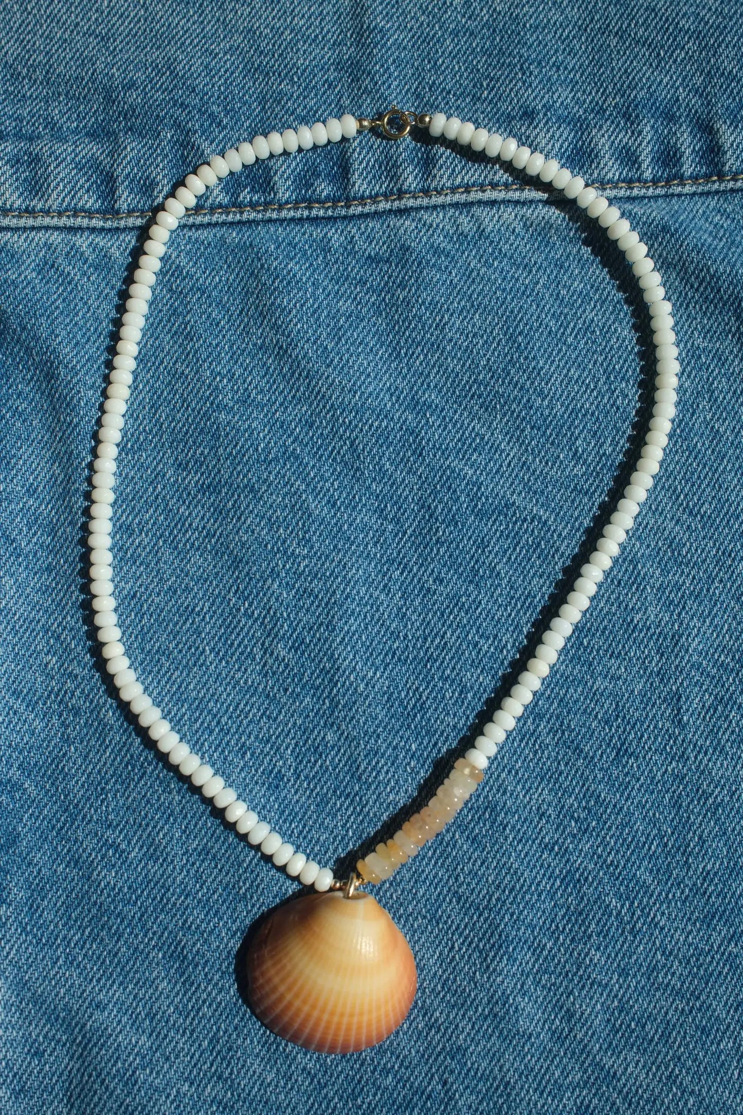 Necklace with a shell pendant on a blue denim background