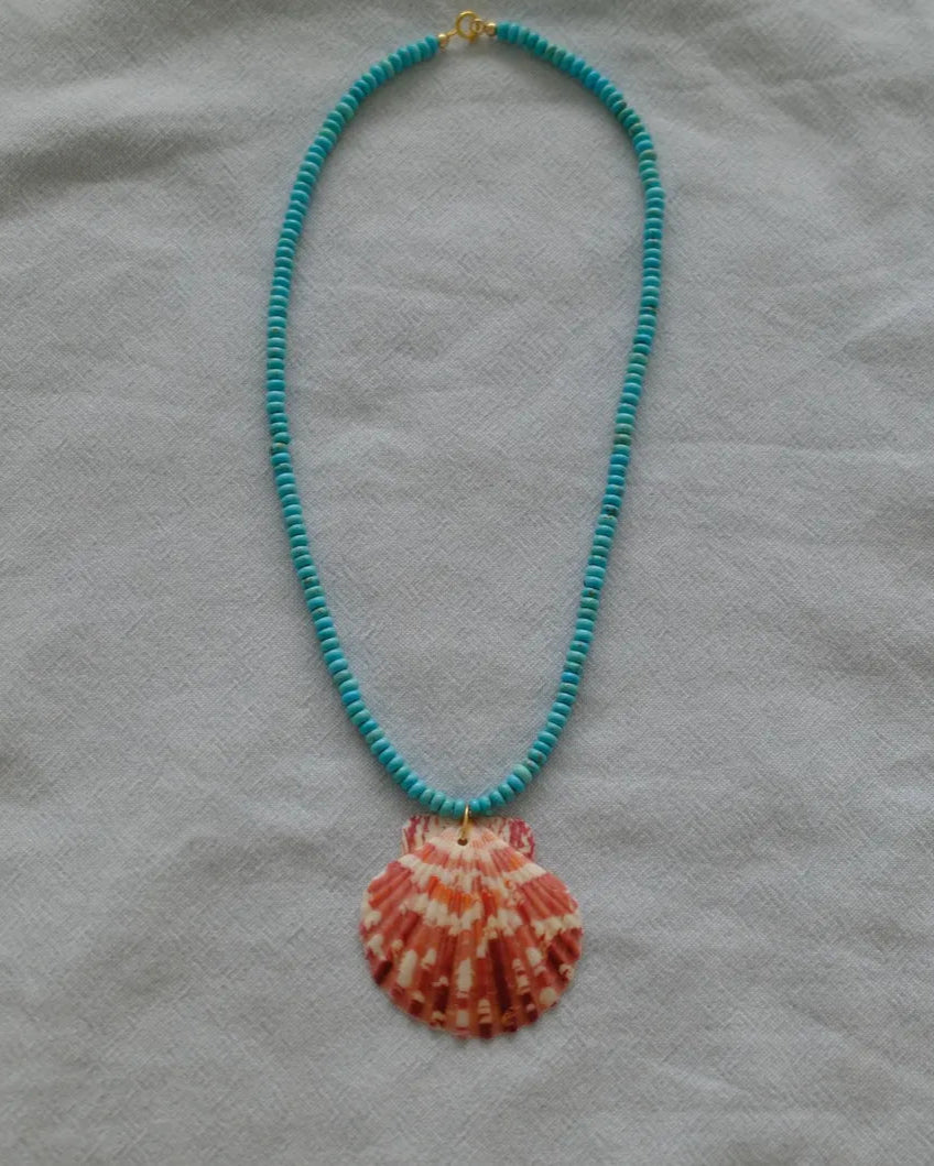 Necklace with a shell pendant on a gray fabric background