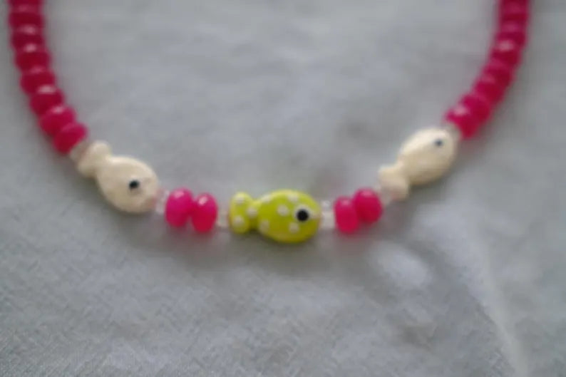Necklace with pink, white, and green beads on a light gray background